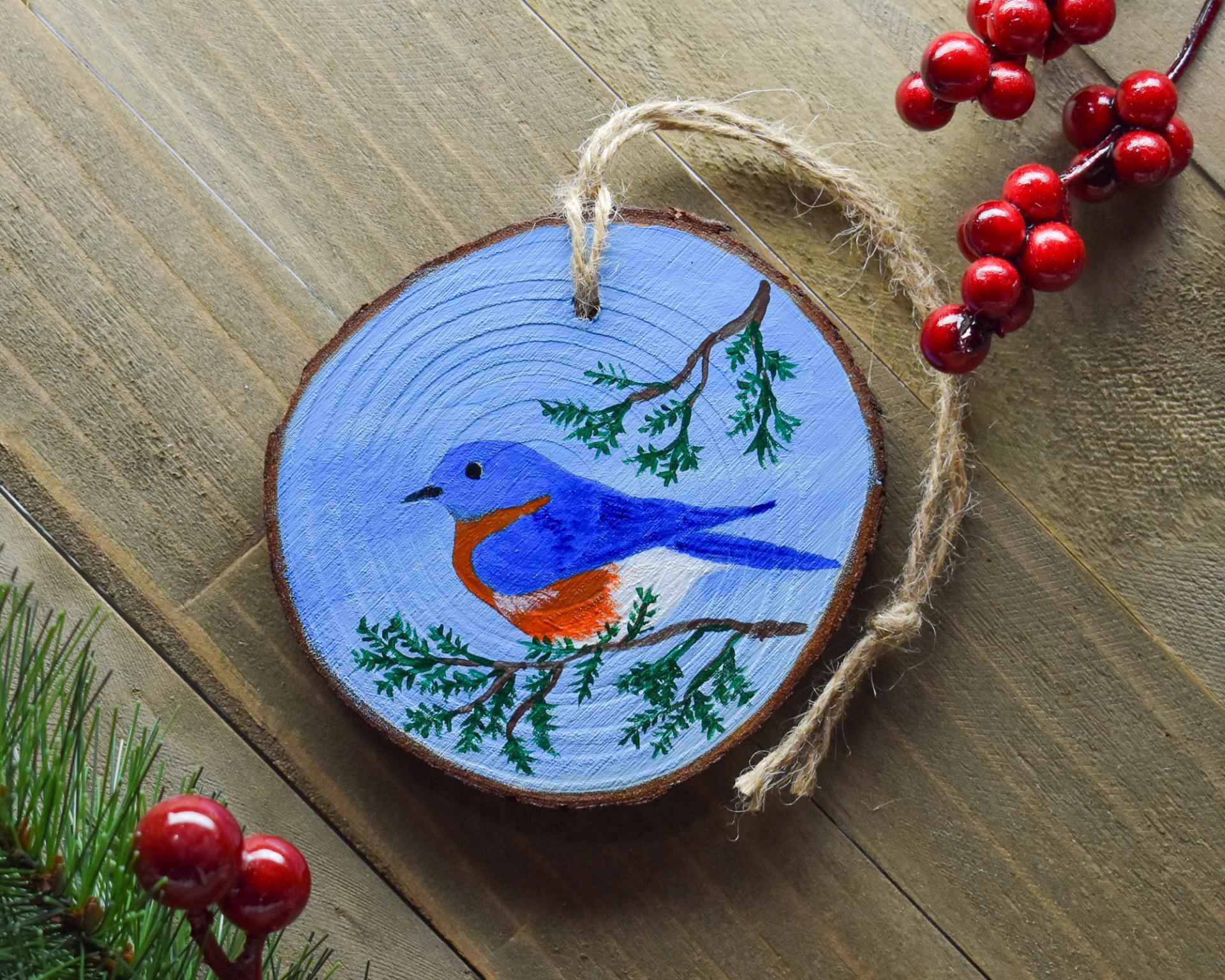 A hand-painted eastern bluebird wood slice Christmas ornament at Cove Creek Photography.