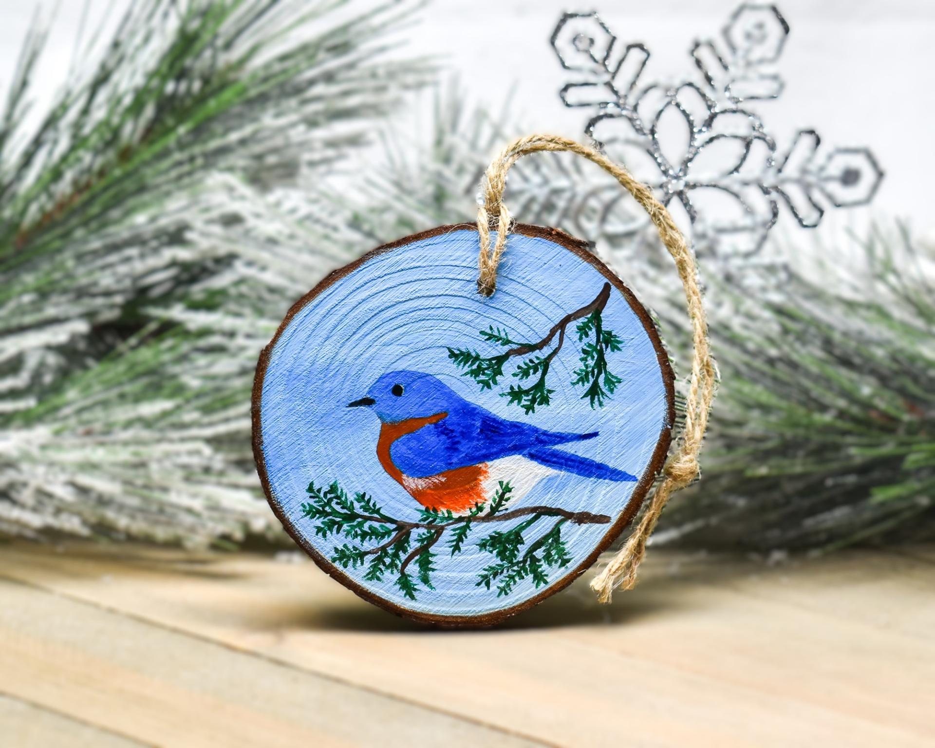 The state bird of New York, an eastern bluebird is hand-painted on a wood slice ornament at covecreekphotography.com.