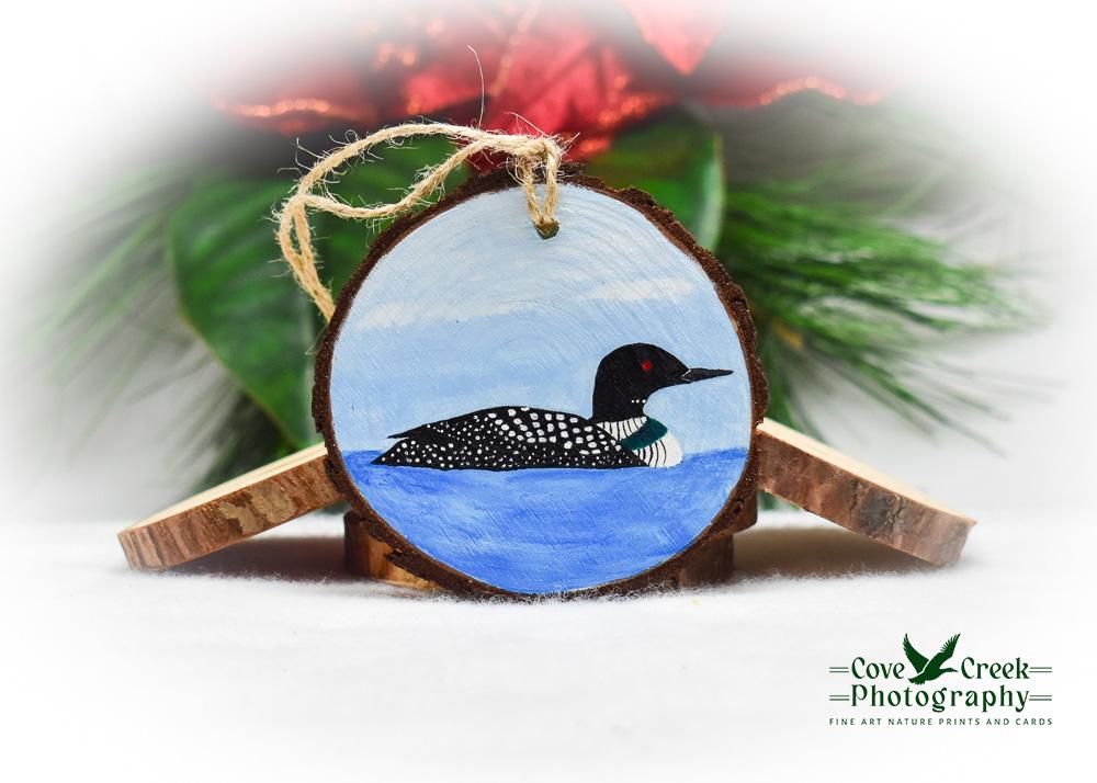 A handmade bird Christmas ornament with a common loon painted on a wood slice at Cove Creek Photography.