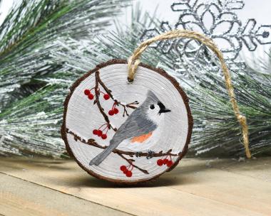 A handmade Christmas ornament with a tufted titmouse hand-painted on a wood slice at covecreekphotography.com.
