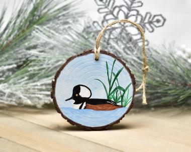 An acrylic painting of a male hooded merganser on a wood slice ornament at covecreekphotography.com.