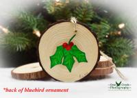 A hand-painted sprig of holly with red berries on the back of a wood slice ornament at Cove Creek Photography.
