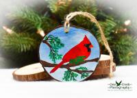The state bird of Ohio, a northern cardinal, is hand-painted on a wood slice Christmas ornament at Cove Creek Photography.