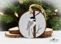A handmade Christmas ornament with a hand-painted bird on a wood slice at covecreekphotography.com.
