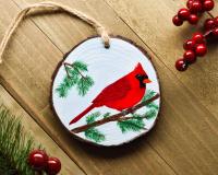 A wood slice Christmas ornament with a hand-painted northern cardinal available at Cove Creek Photography.