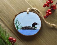 A hand-painted common loon Christmas ornament displayed on weathered boards at Cove Creek Photography.