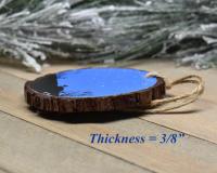 An image showing the thickness of a handmade wood slice Christmas ornament at Cove Creek Photography.
