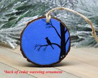 A hand-painted starry sky with a silhouette of a bird perched in a tree on a wood slice ornament at covecreekphotography.com.