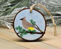 A hand-painted wood slice Christmas ornament with a cedar waxwing perched on a tree limb at Cove Creek Photography.