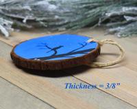 A display of a hand-painted wood slice ornament showing the 3/8" thickness of the slice at Cove Creek Photography.