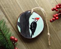 The front view of a hand-painted pileated woodpecker wood slice Christmas ornament at Cove Creek Photography.
