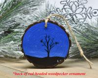 A hand-painted starry night with a silhouette of birds in a tree on a wood slice Christmas ornament at covecreekphotography.com.
