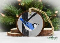 A handmade bird Christmas ornament with a hand-painted nuthatch in the snow at covecreekphotography.com.