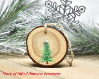 An evergreen tree hand-painted on the back of a tufted titmouse wood slice ornament at covecreekphotography.com.