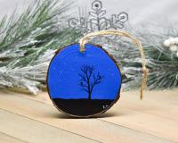 A hand-painted wood slice ornament with a night sky and bird and tree silhouettes at covecreekphotography.com.