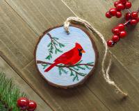 A handmade northern cardinal wood slice Christmas ornament at Cove Creek Photography.