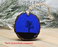 An ornament with a hand-painted silhouette of a tree and birds against a dark blue starry background at Cove Creek Photgraphy.