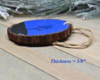 A display of a hand-painted wood slice Christmas ornament showing the thickness of the wood slice.