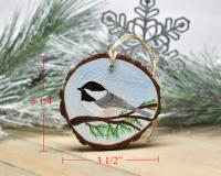 A handmade chickadee wood slice ornament with the measurements displayed on each side at covecreekphotography.com.