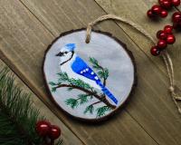A handmade wood slice ornament with a hand-painted blue jay at covecreekphotography.com