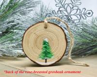 The back of a handmade wood slice ornament with hand-painted evergreen tree in snow at Cove Creek Photography.