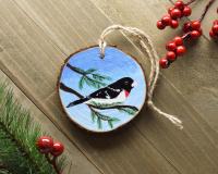 A male rose-breasted grosbeak hand-painted onto a wood slice ornament at Cove Creek Photography.