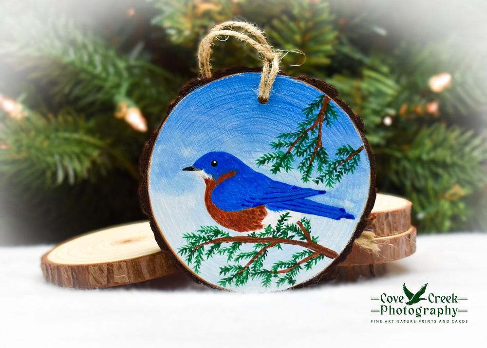 An eastern bluebird, the state bird of Missouri, is hand-painted on a wood slice ornament at Cove Creek Photography.