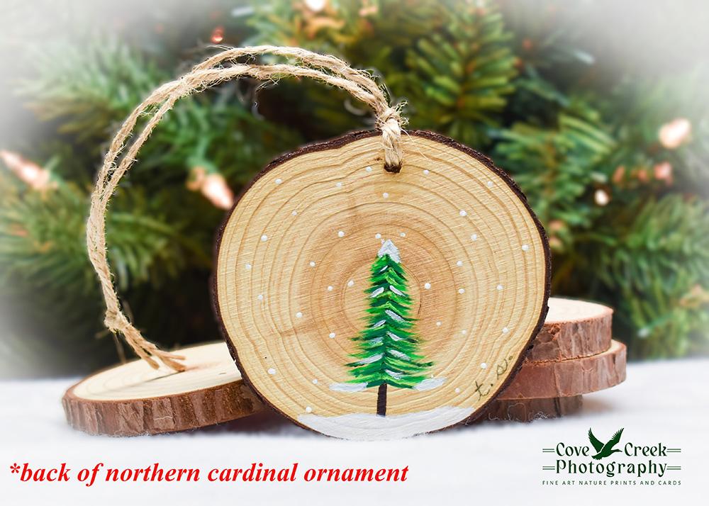 A hand-painted evergreen tree on the back of a northern cardinal Christmas ornament at covecreekphotography.com.