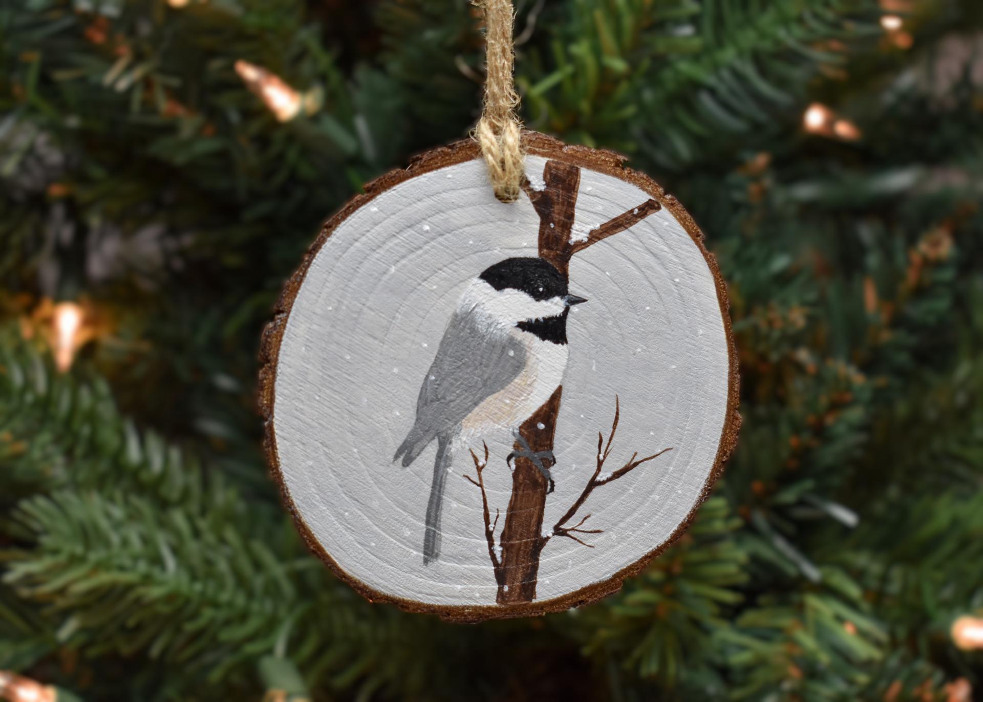 A hand-painted chickadee in the snow wood slice Christmas ornament at Cove Creek Photography.