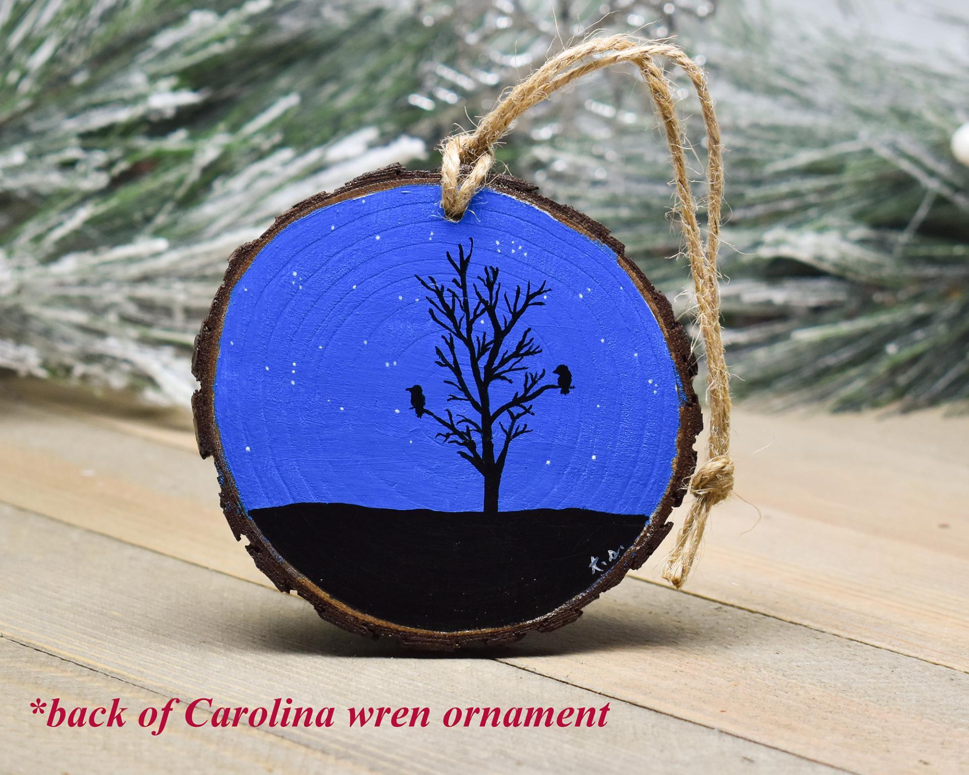 A hand-painted wood slice ornament with a starry night sky and bird and tree silhouette at Cove Creek Photography.