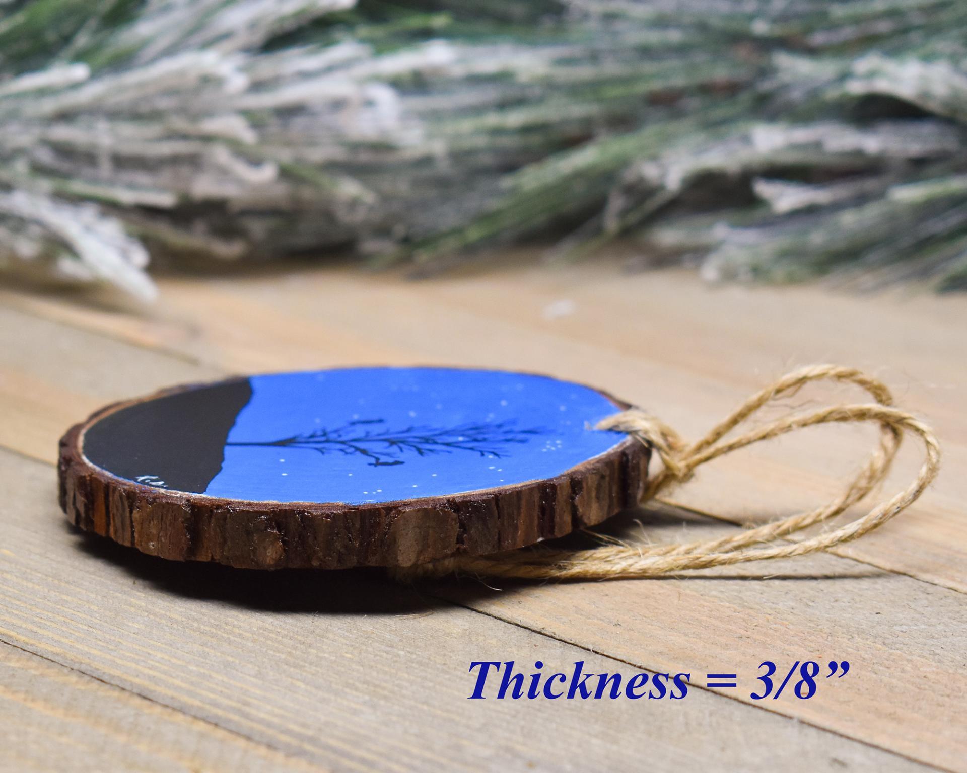 An image of the side of a hand-painted Christmas ornament displaying the bark and thickness of the wood slice at Cove Creek Photography. 
