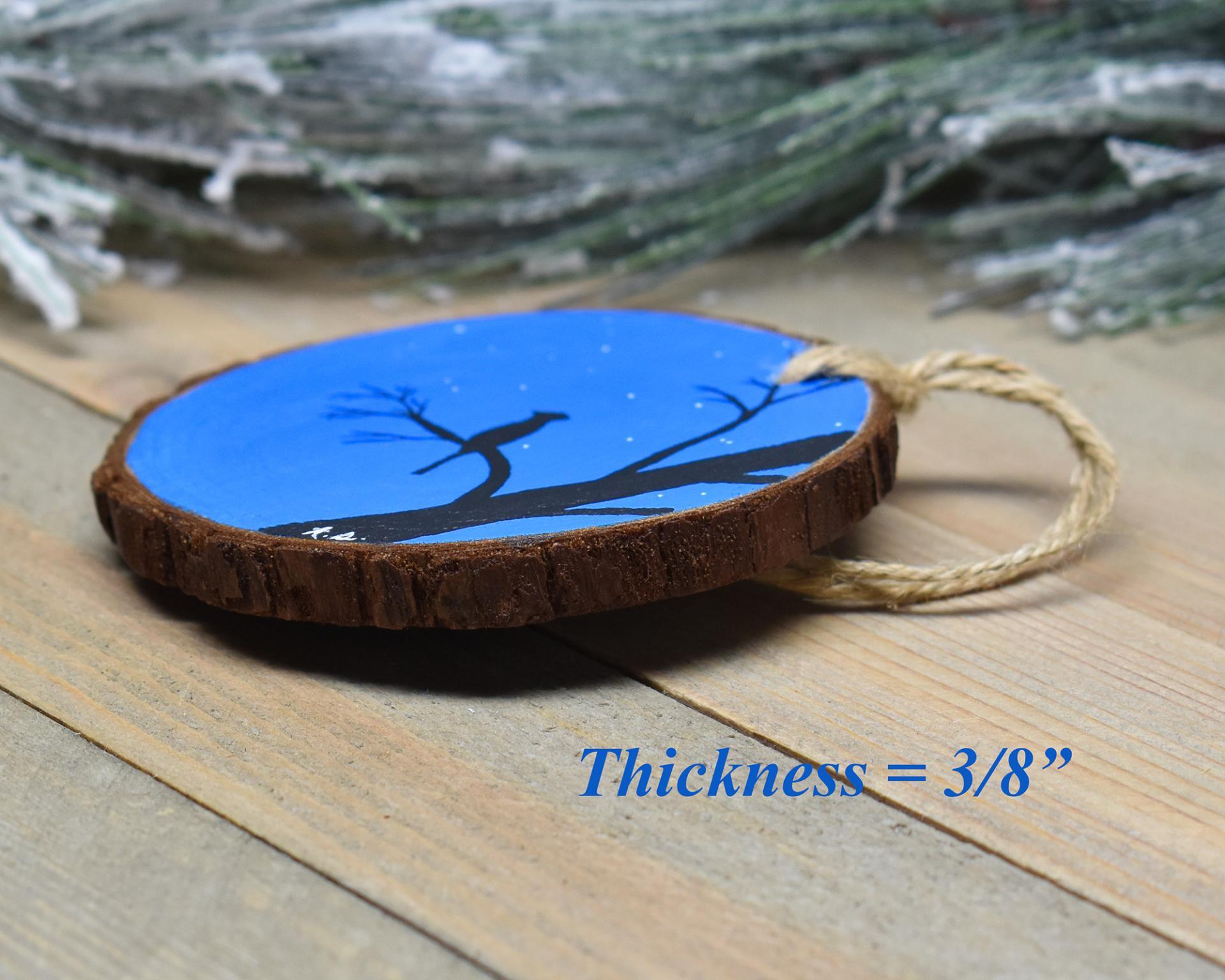 A display of a hand-painted wood slice ornament showing the 3/8" thickness of the slice at Cove Creek Photography.
