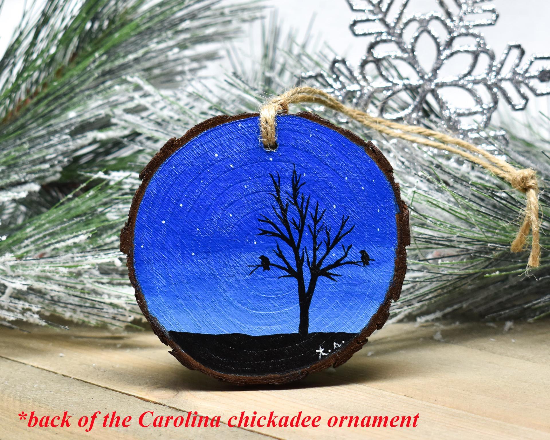 A dark blue starry winter night with a silhouette of a tree and roosting birds hand-painted on a wood slice ornament at covecreekphotography.com.