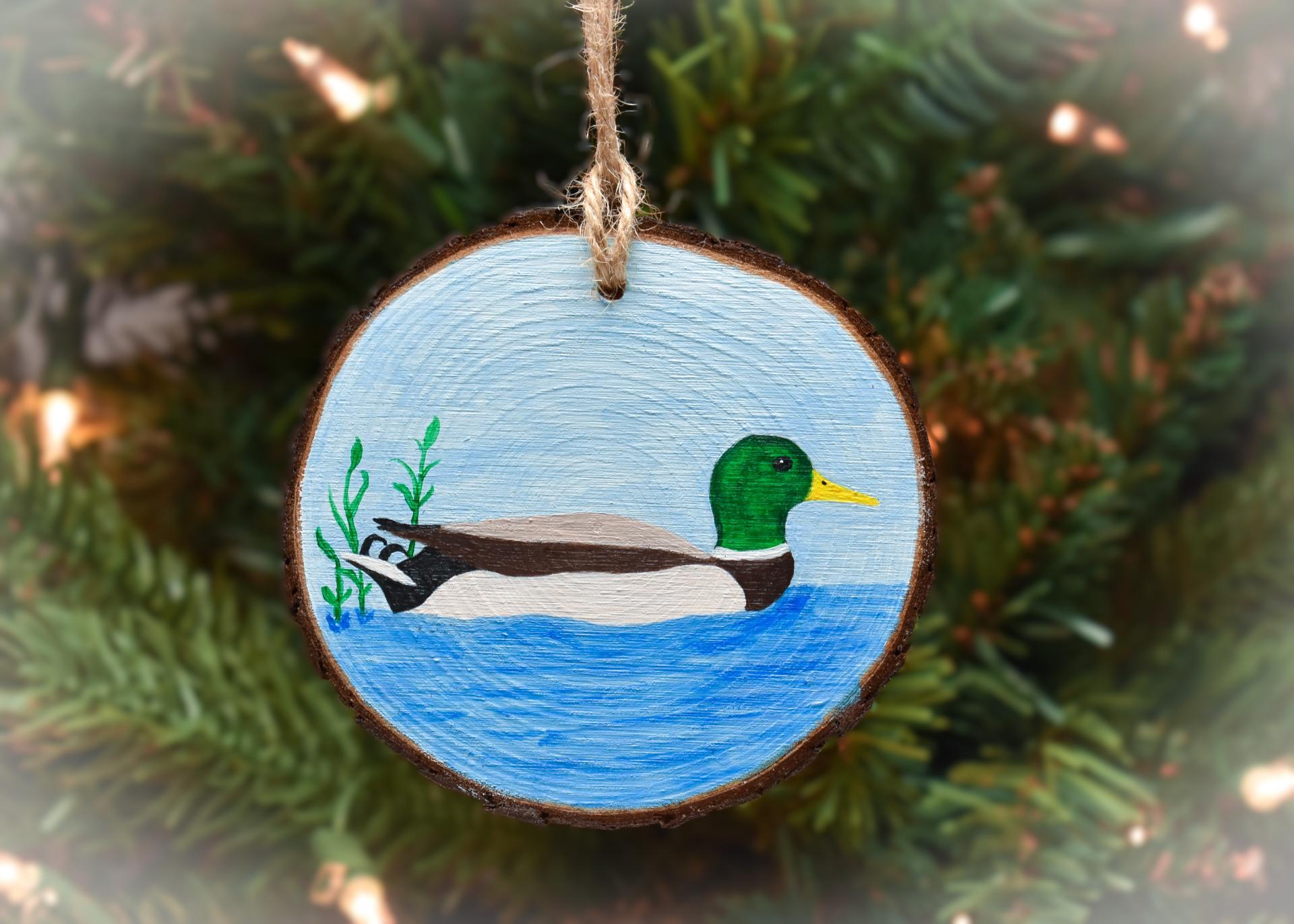 A wood slice Christmas ornament with a hand-painted mallard drake at Cove Creek Photography.