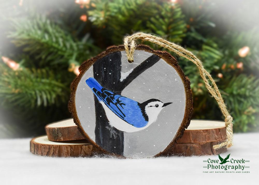 A handmade bird Christmas ornament with a hand-painted nuthatch in the snow at covecreekphotography.com.