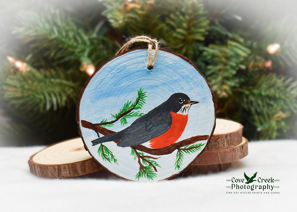 A handmade wood slice Christmas ornament with a hand-painted American Robin at Cove Creek Photography.