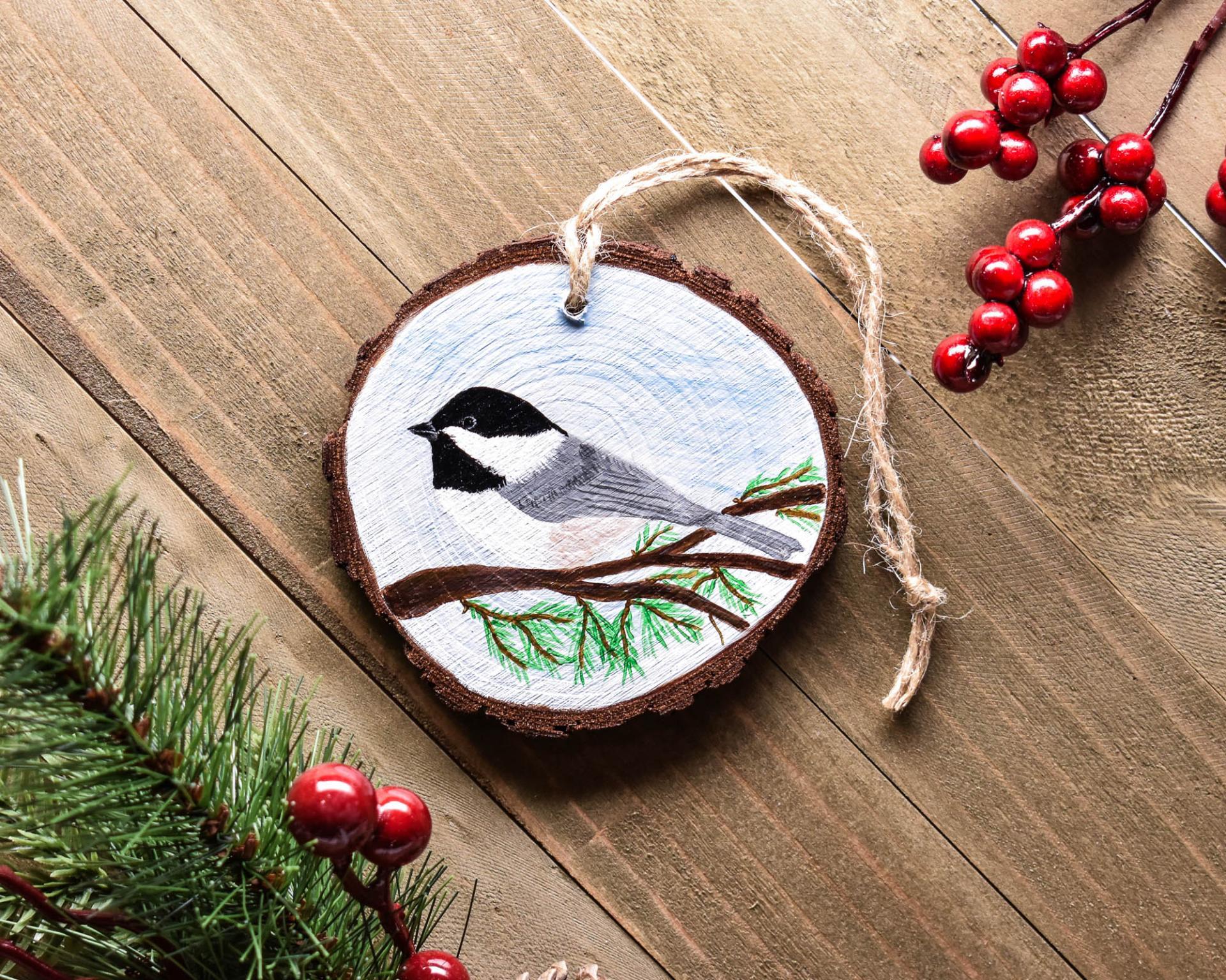 An acrylic painting of a Carolina chickadee on a three inch wood slice at Cove Creek Photography.