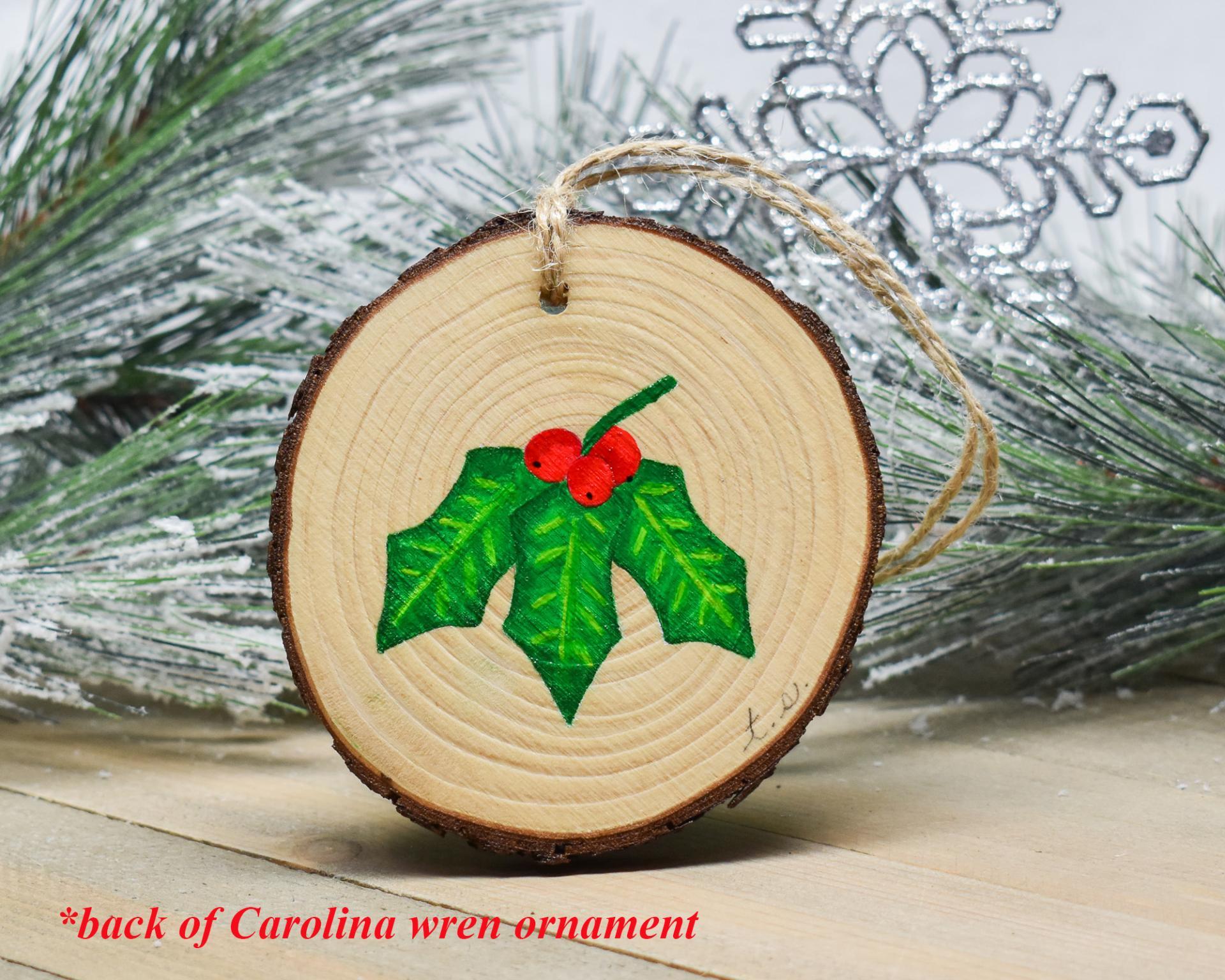 Holly leaves with red berries are hand-painted on a wood slice ornament at covecreekphotography.com.