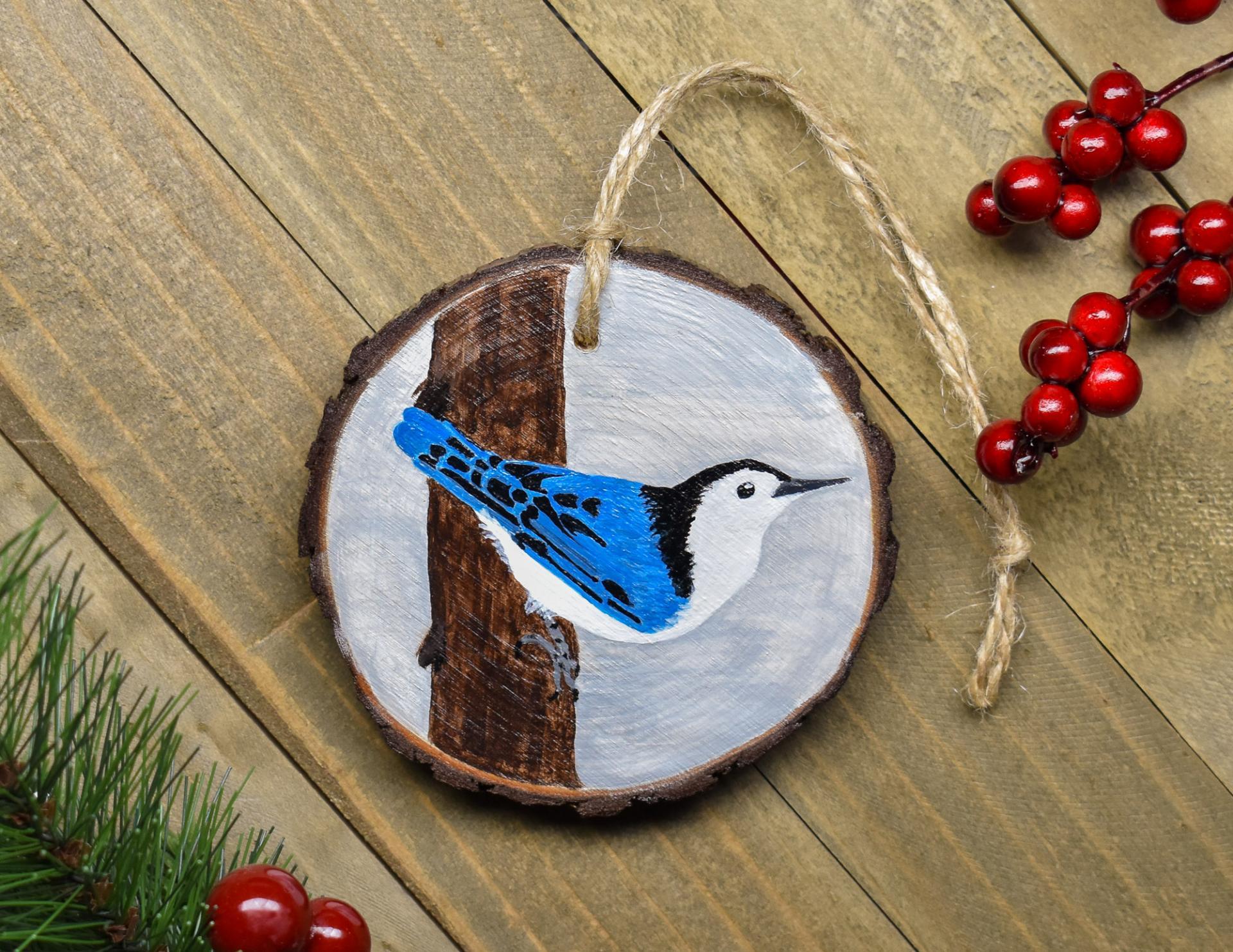 A wood slice Christmas ornament witha hand-painted white-breasted nuthatch at covecreekphotography.com.