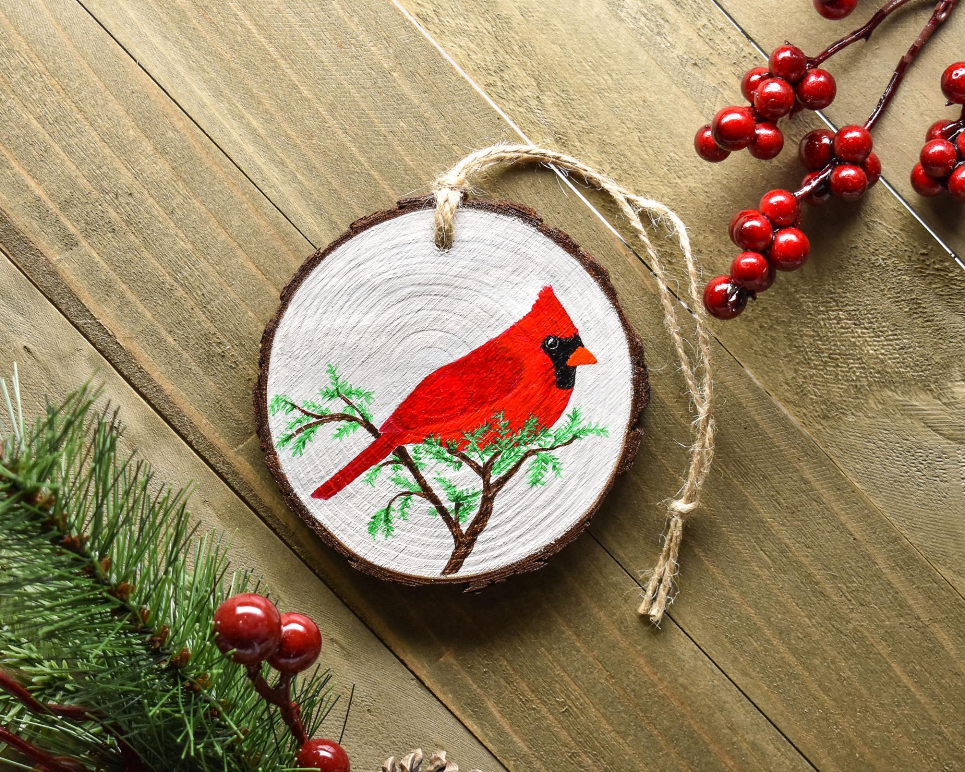 A hand-painted male northern cardinal on a wood slice Christmas ornament at covecreekphotography.com.