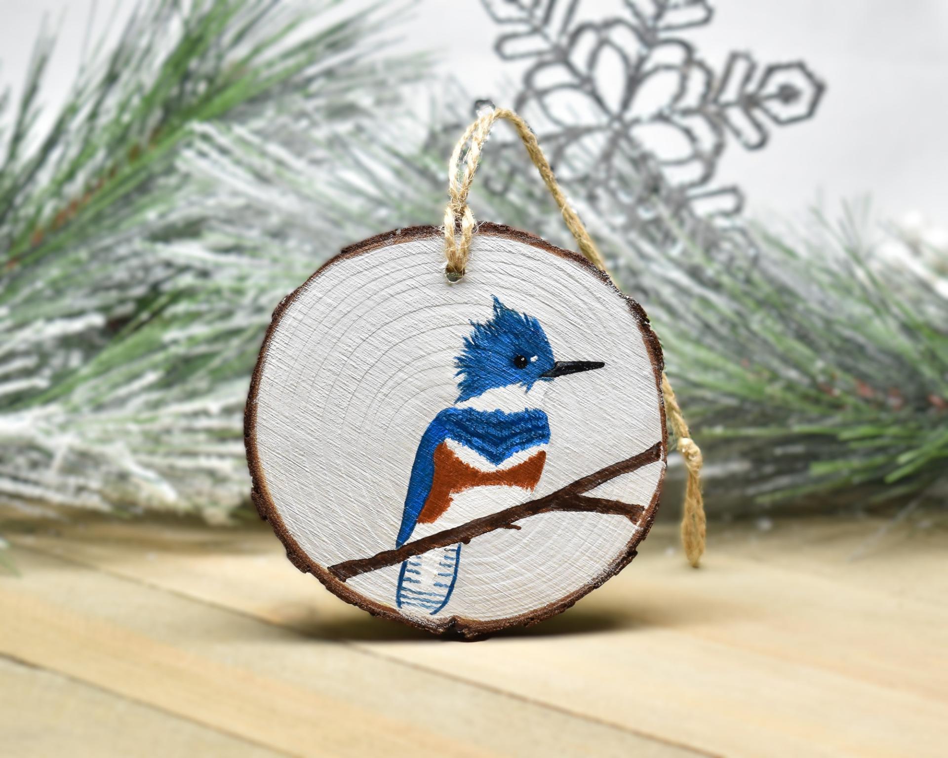 An acrylic painting of a female belted kingfisher on a wood slice Christmas ornament at covecreekphotography.com.