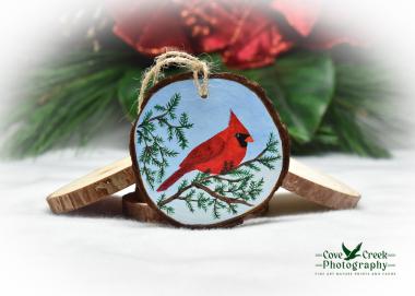 A hand-painted wood slice ornament with a brilliant red northern cardinal available at Cove Creek Photography.