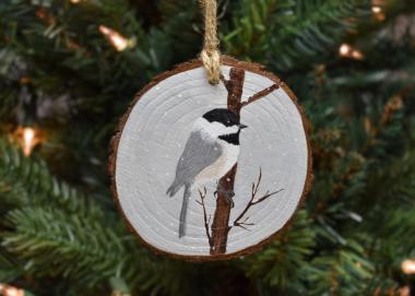 A hand-painted chickadee in the snow wood slice Christmas ornament at Cove Creek Photography.