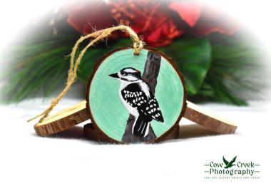 A hand-painted downy woodpecker on a wood slice ornament available for purchase at covecreekphotography.com.