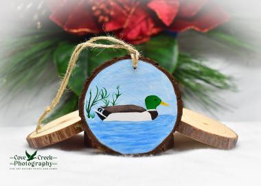 A hand-painted wood slice ornament featuring a mallard on blue water that is available at Cove Creek Photography.