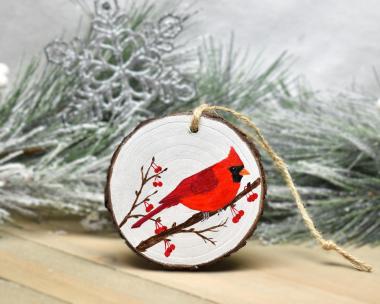 An acrylic painting on a wood slice of a cardinal on a tree branch with red berries at covecreekphotography.com.