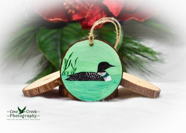A hand-painted common loon on a pond wood slice ornament available for purchase at Cove Creek Photography.