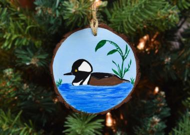 Hand-painted male hooded merganser on a wood slice ornament hanging on a Christmas tree at www.covecreekphotography.com.