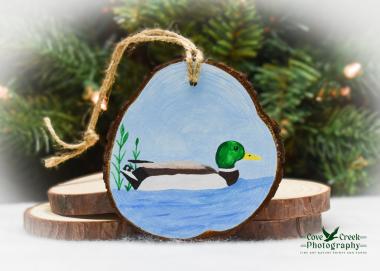 A hand-painted mallard on a pear shaped wood slice Christmas ornament at Cove Creek Photography.